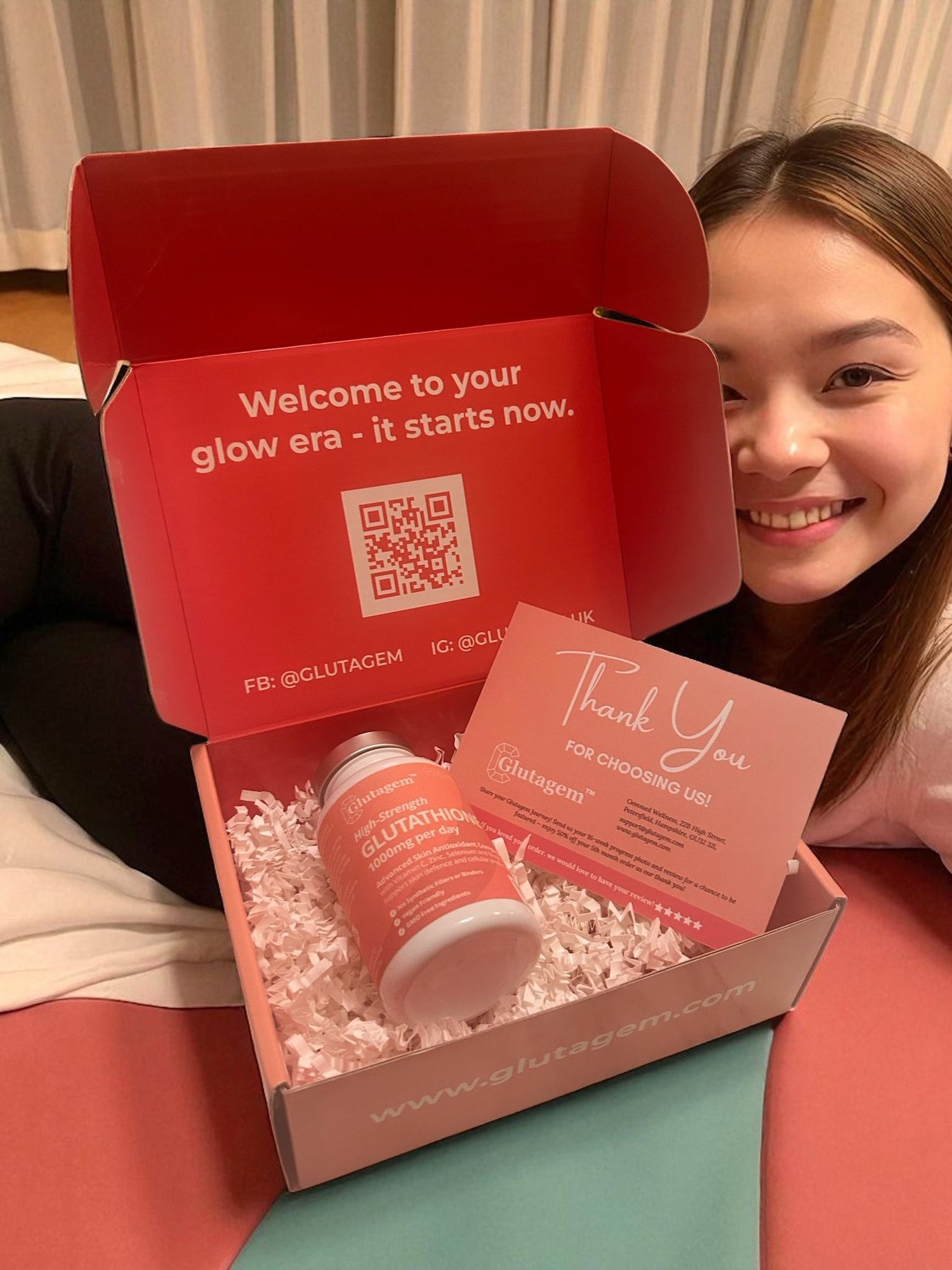 Woman with a Glutagem product box containing a Glutathione 1000mg tub and thank-you card, with Glutagem branding text.